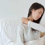 Woman feeling shoulder pain on bed