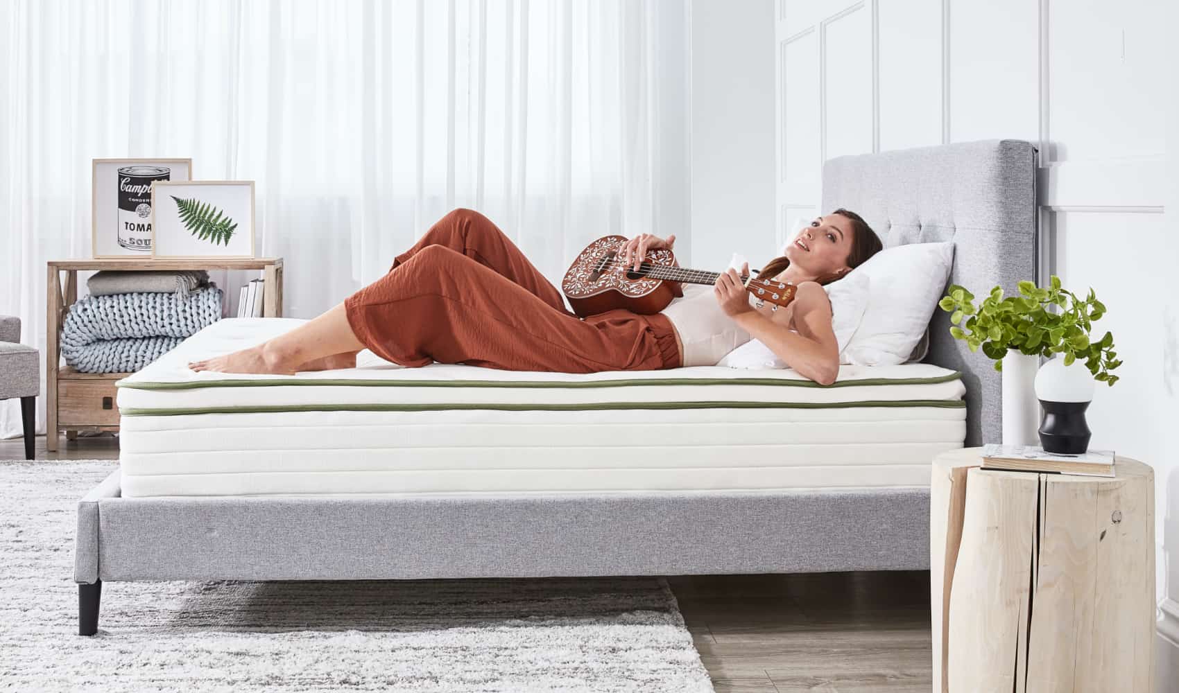 Woman lying on back on bed playing a ukulele