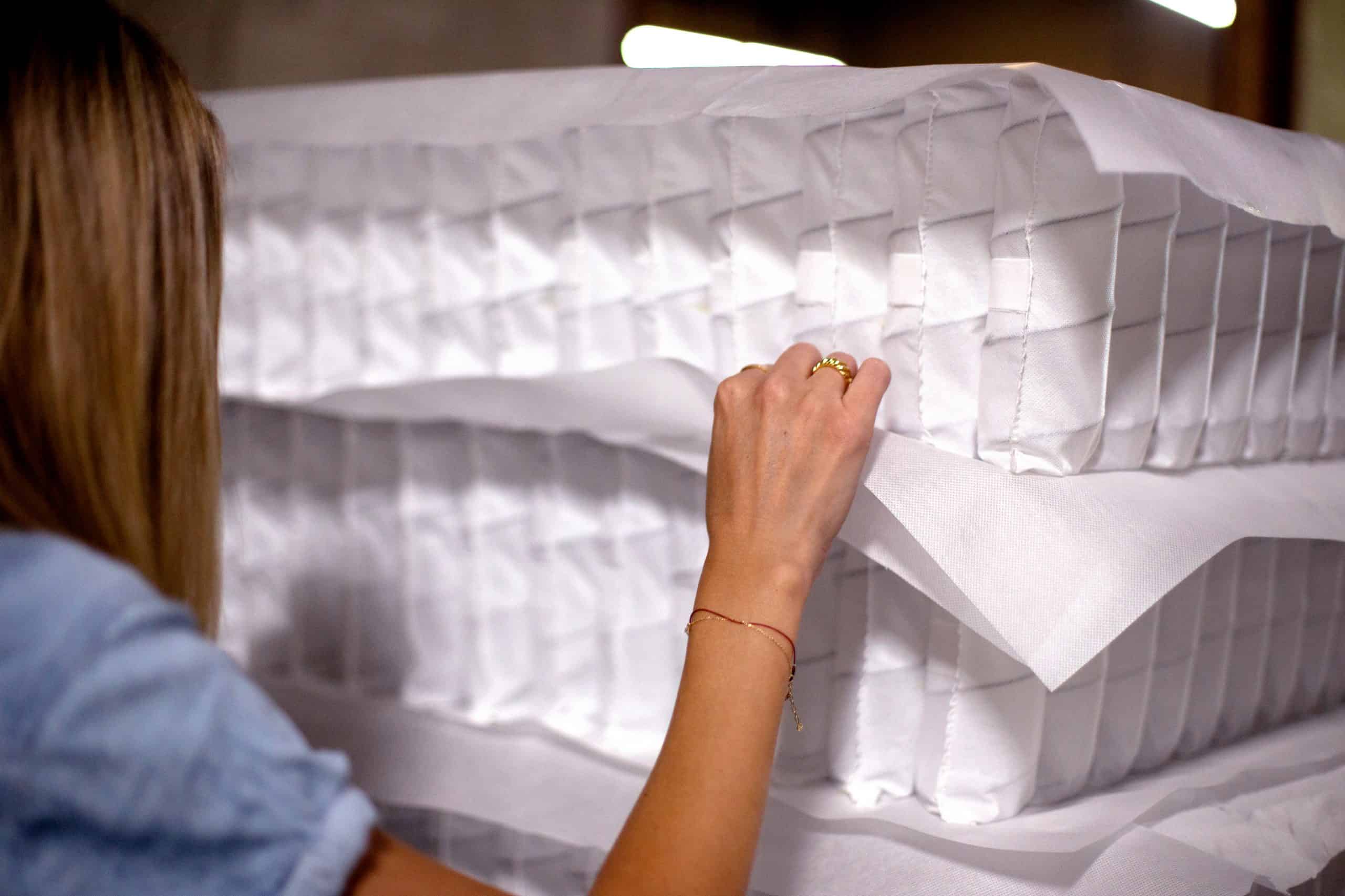 Woman feels the fabric between spring sets at spring factory in Toronto, Ontario.