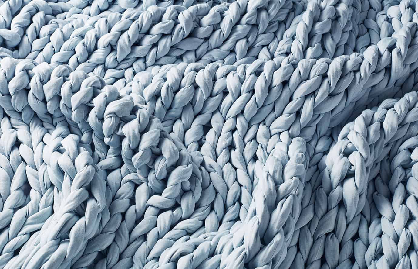 Close up of a baby blue hand-knit weighted blanket.